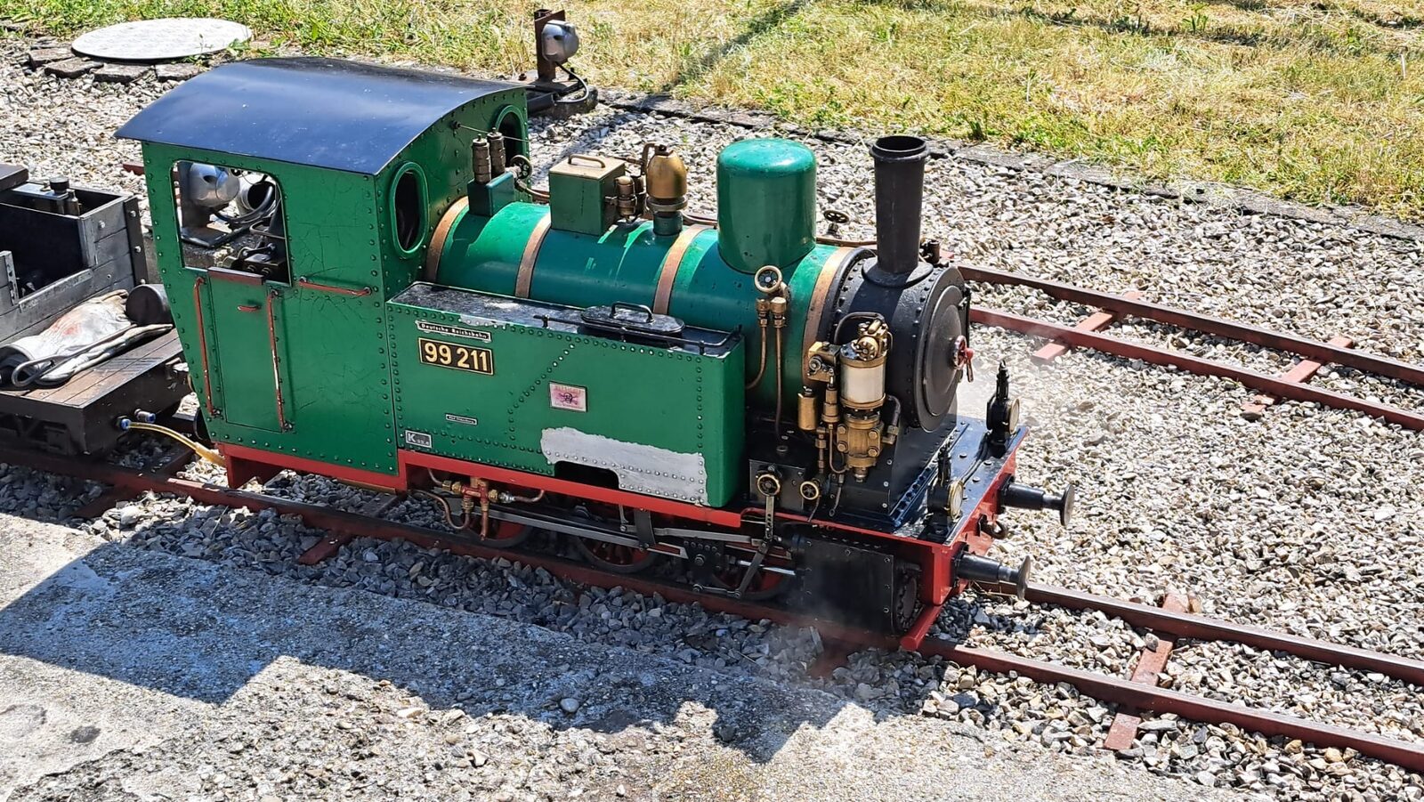 Grüne Dampflokomotive 99 211 der Gartenbahn in Spur 5 auf dem Gleis des Vereinsgeländes
