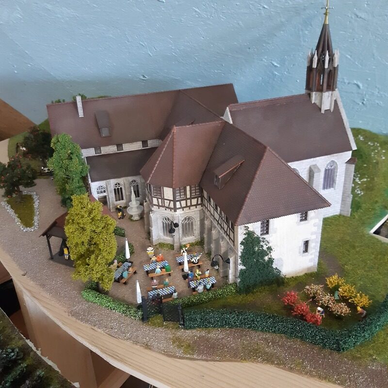 Kirche mit Fachwerkanbau und Biergarten als Modell auf der H0-Anlage
